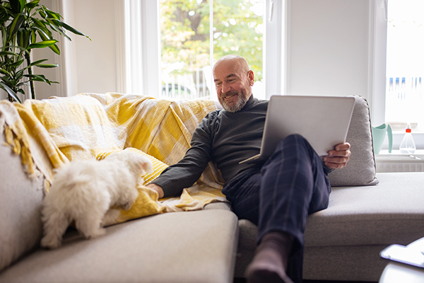 Man sitting with laptop and dog on couch